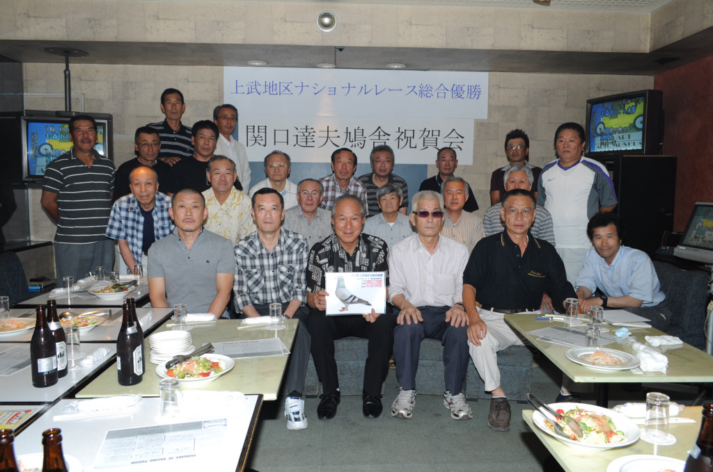 ★上武連盟の鳩友が多数祝福に駆けつけ、関口達夫鳩舎の地区N総合優勝及び3代連続連盟優勝の快挙を讃えた。写真前列左から3番目がヒーローの関口達夫鳩舎。右隣が並木・上武連盟長。前列1番左は林・東クラブ長。